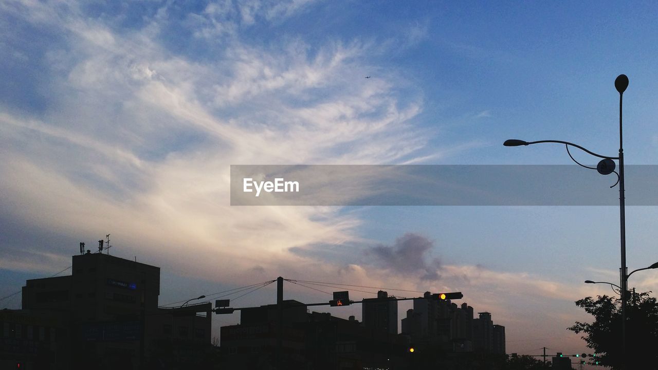 SILHOUETTE OF BUILDINGS AGAINST CLOUDY SKY