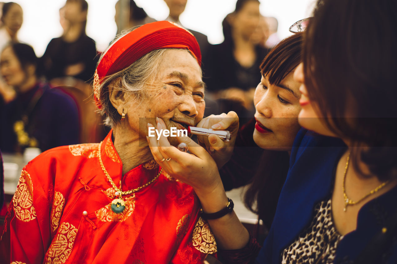 Close-up of woman applying lipstick on mother lips