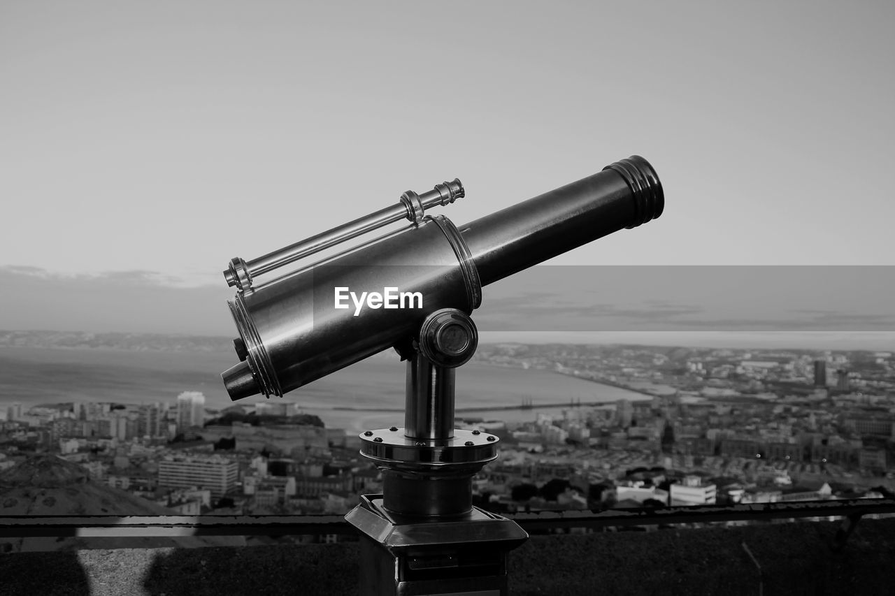 Close-up of coin-operated binoculars against cityscape