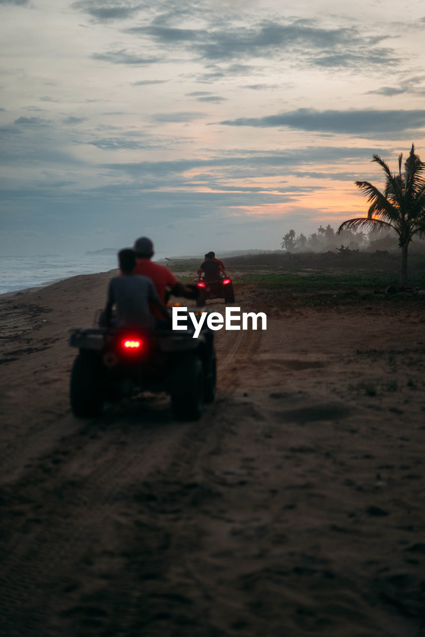 People riding quadbikes on sand at beach