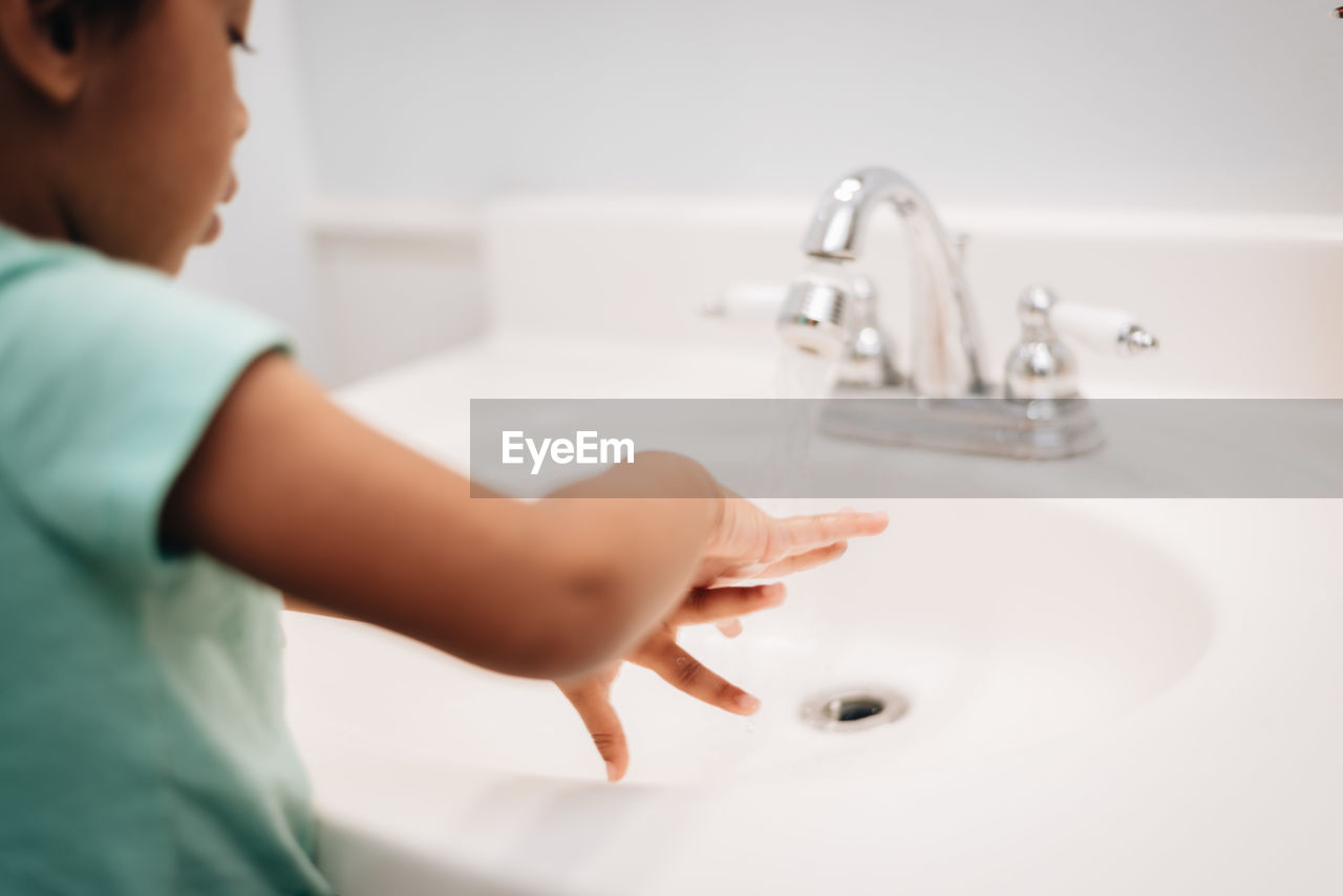 Pre school age girl at home washing hands in bathroom