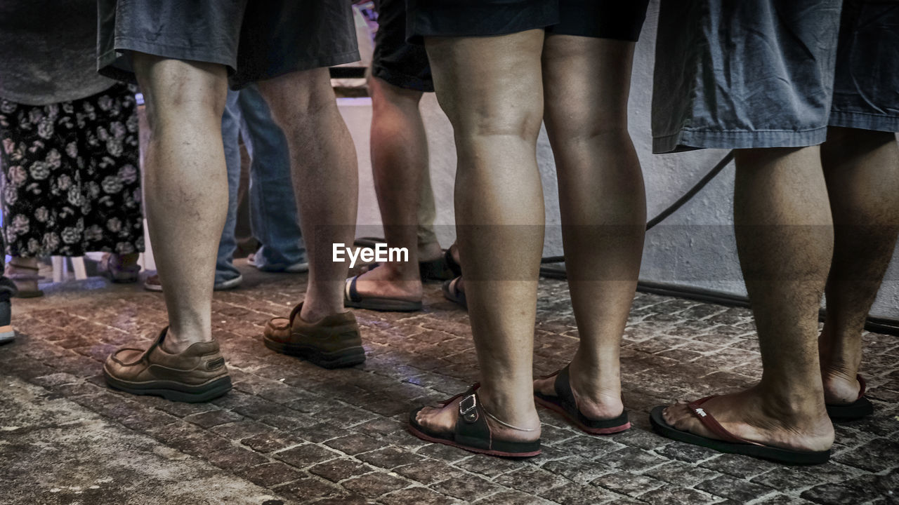 LOW SECTION OF PEOPLE STANDING ON FLOOR IN CITY AT NIGHT