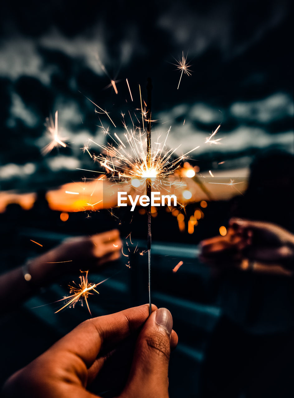 Selective focus of several hands holding fireworks at dusk. creative background template.
