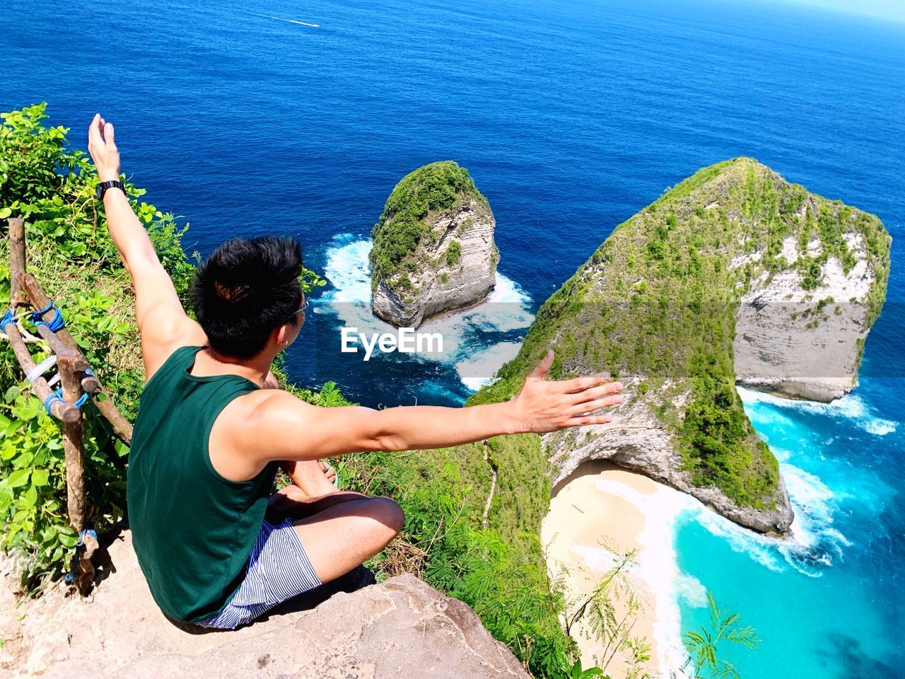 High angle view of man sitting on rock over sea