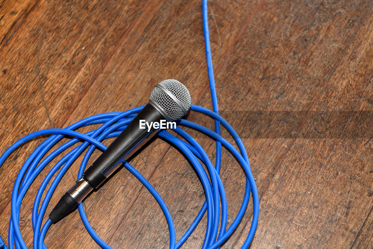 High angle view of microphone and blue cable on table