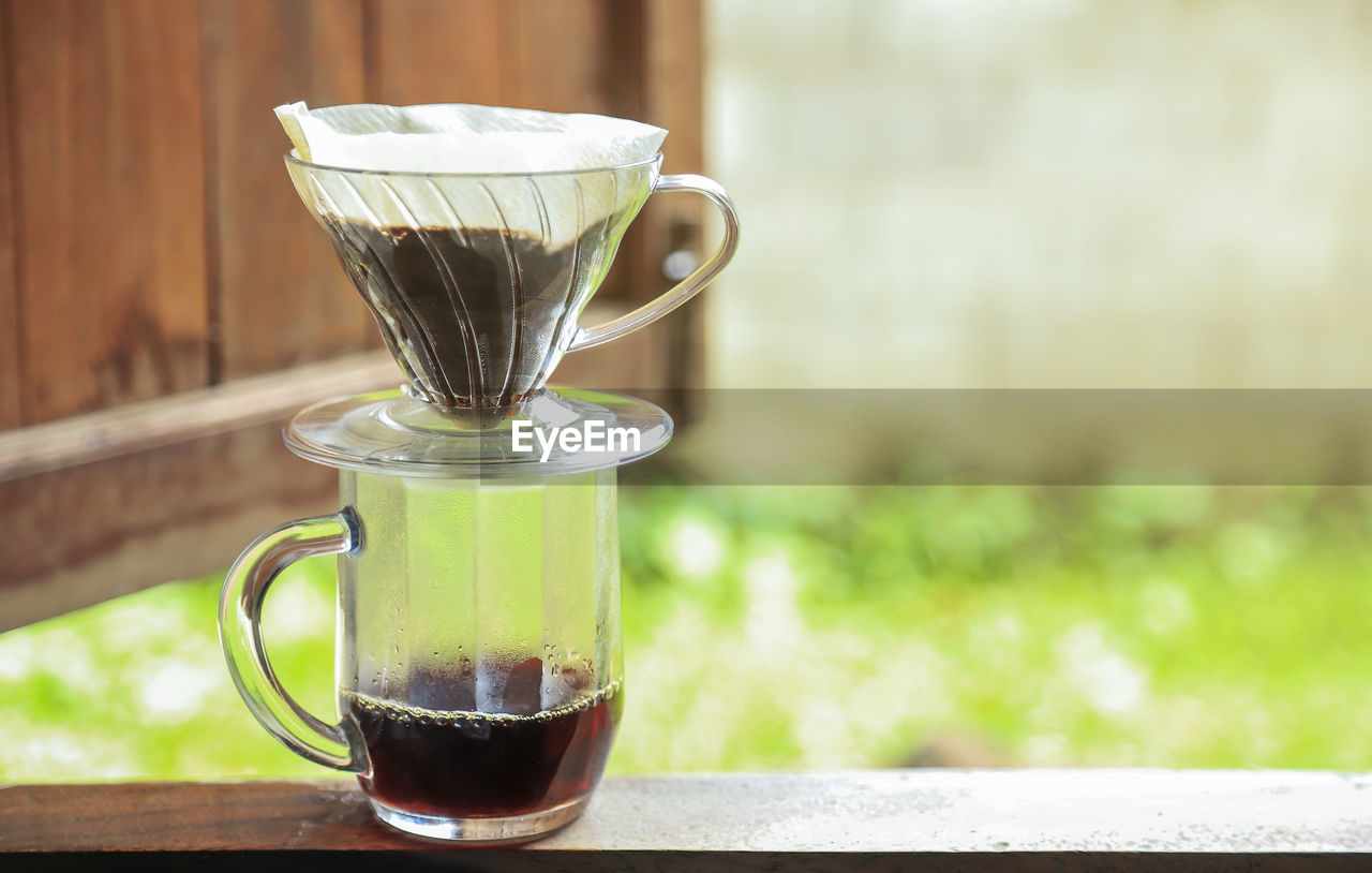 CLOSE-UP OF COFFEE IN GLASS ON TABLE