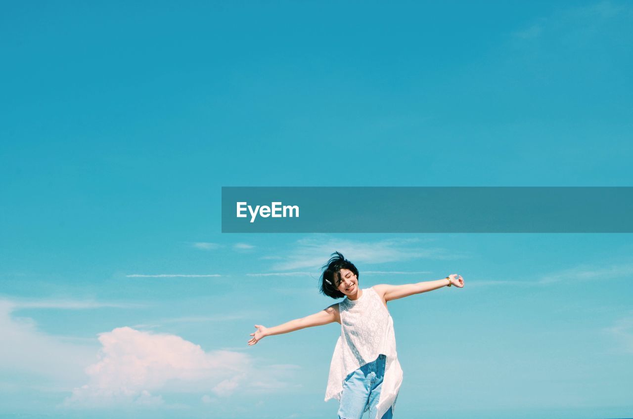 Low angle view of woman standing against blue sky