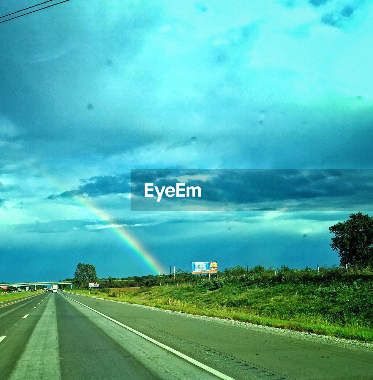 RAINBOW OVER AGRICULTURAL FIELD AGAINST BLUE SKY