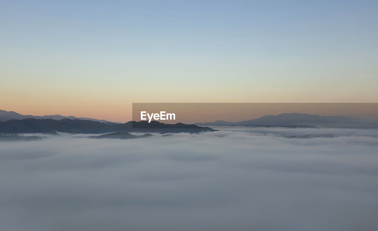 sky, scenics - nature, beauty in nature, mountain, cloud, environment, tranquility, tranquil scene, dawn, sunrise, mountain range, nature, landscape, no people, morning, winter, copy space, idyllic, cold temperature, horizon, snow, fog, outdoors, sunlight, travel, blue, aerial view, sun, non-urban scene, dramatic sky