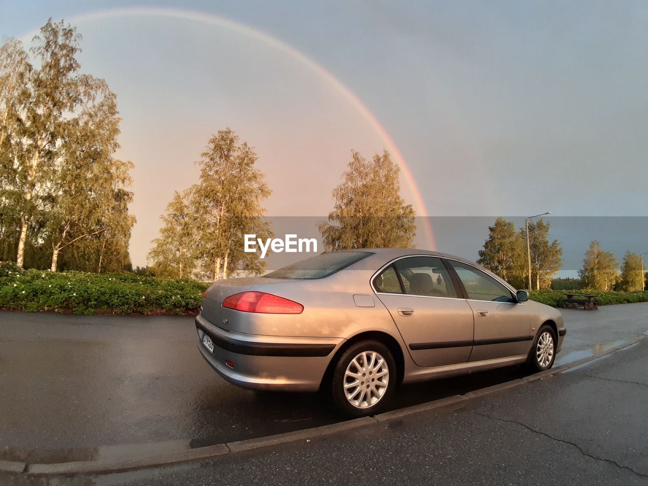 VIEW OF CARS PARKED ON ROAD AGAINST RAINBOW