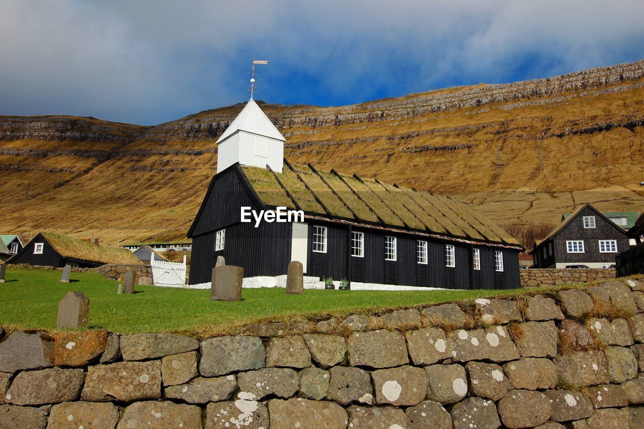 TRADITIONAL BUILDING BY MOUNTAINS AGAINST SKY