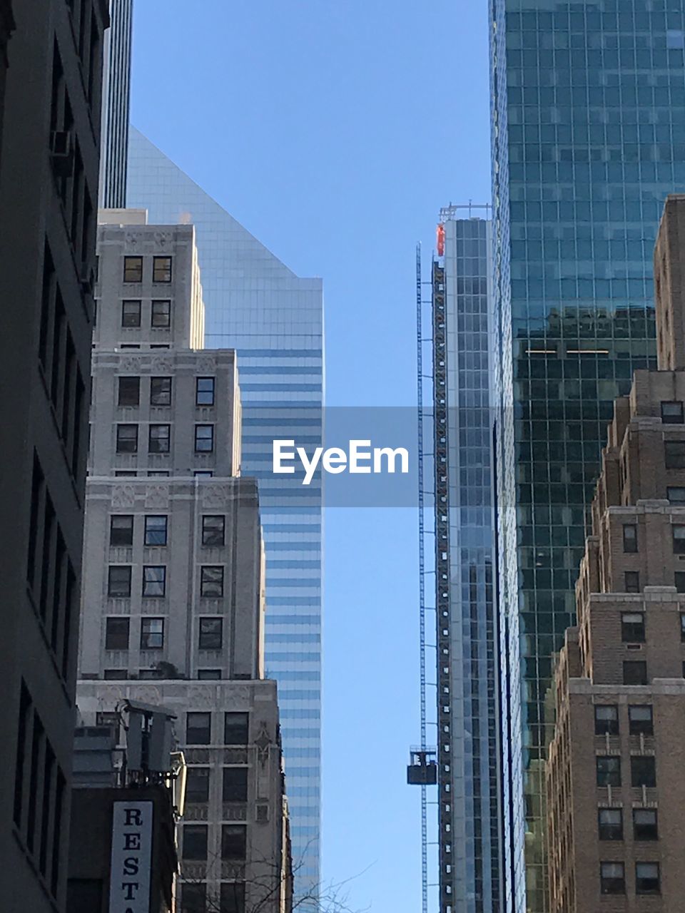 LOW ANGLE VIEW OF BUILDINGS AGAINST CLEAR BLUE SKY