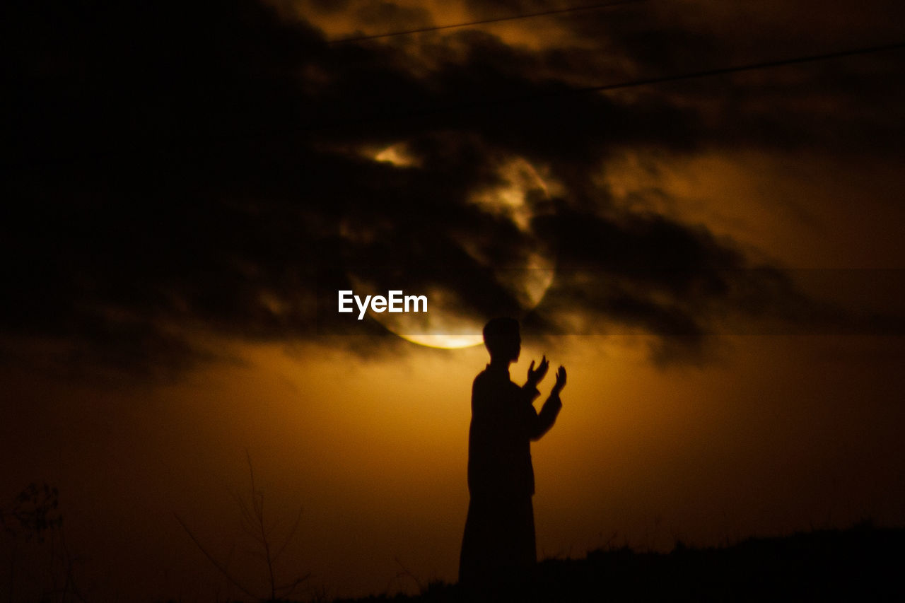 SILHOUETTE MAN STANDING AGAINST DRAMATIC SKY