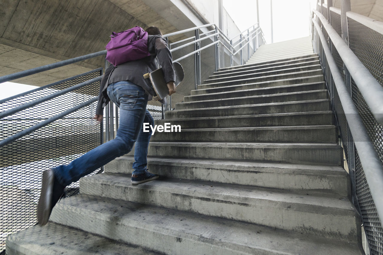 Man with skateboard running on steps