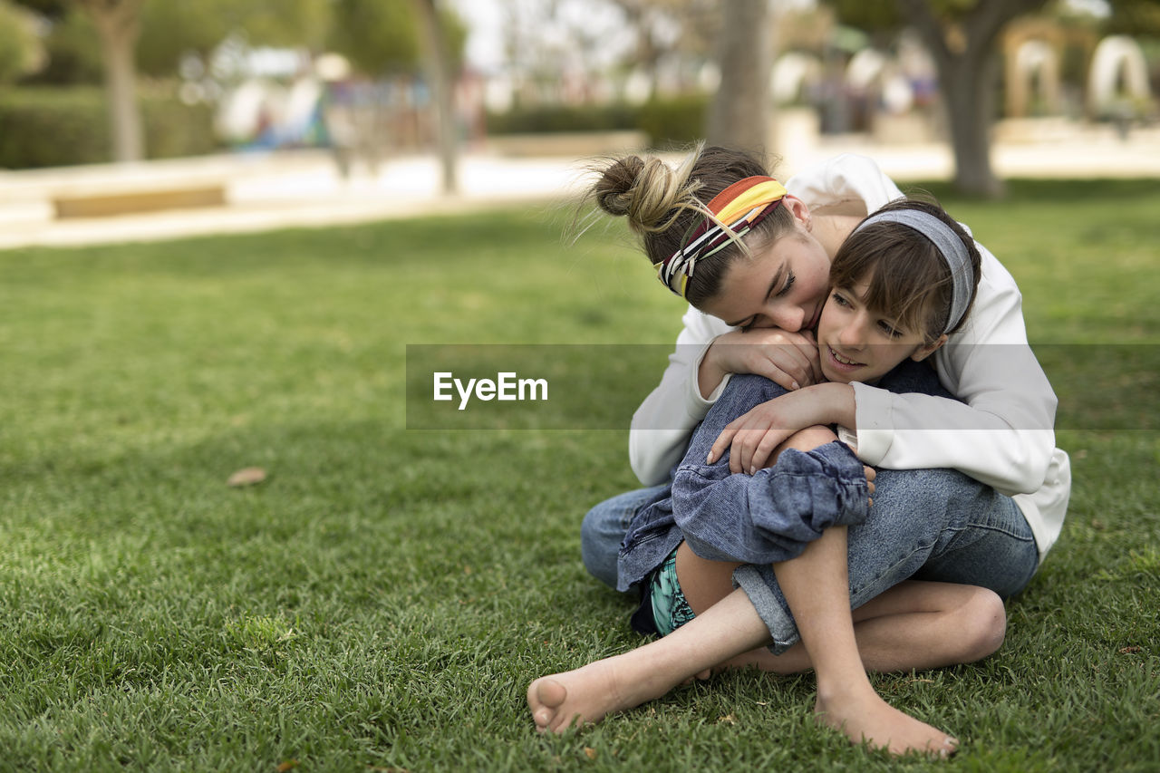 Full length of siblings embracing on field at park