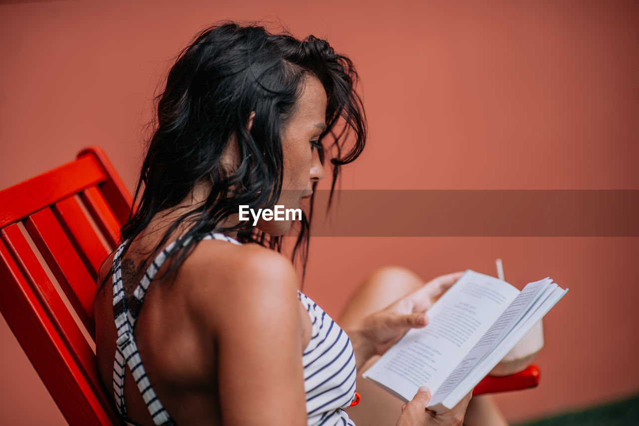 MIDSECTION OF WOMAN HOLDING PAPER AGAINST WALL