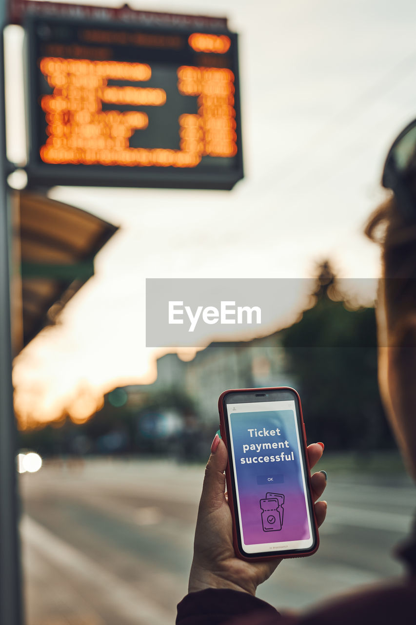 Buying ticket online near bus stop before ride. person paying for ticket using mobile payment app