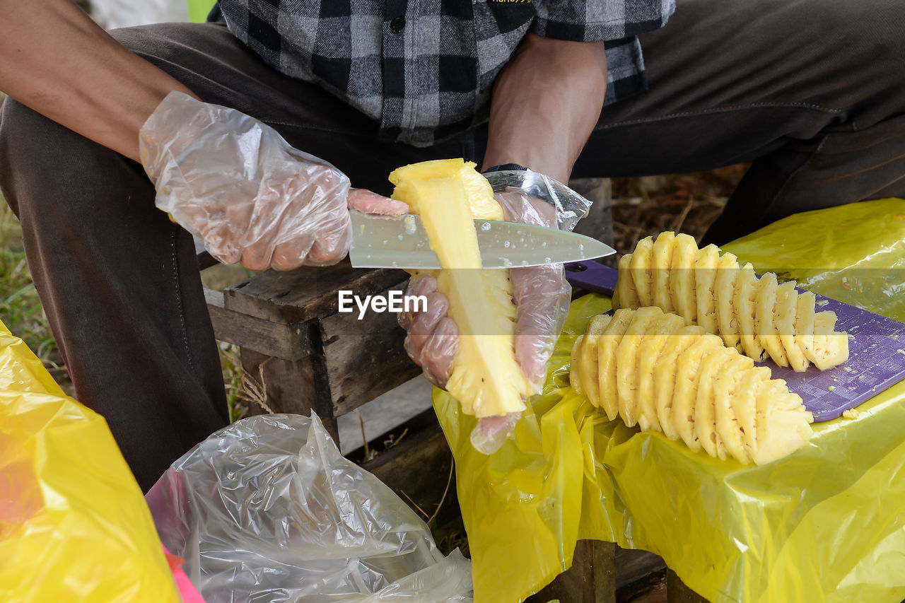 yellow, vegetable, food and drink, food, midsection, adult, one person, sweet corn, plastic, freshness, holding, men, plastic bag, business finance and industry, healthy eating, occupation, business, protection, corn, working, outdoors, container, hand, protective glove