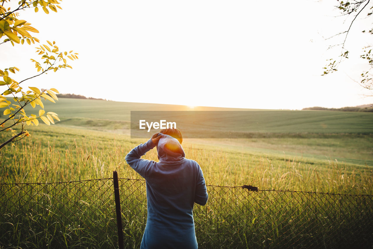 Rear view of woman standing on field against clear sky