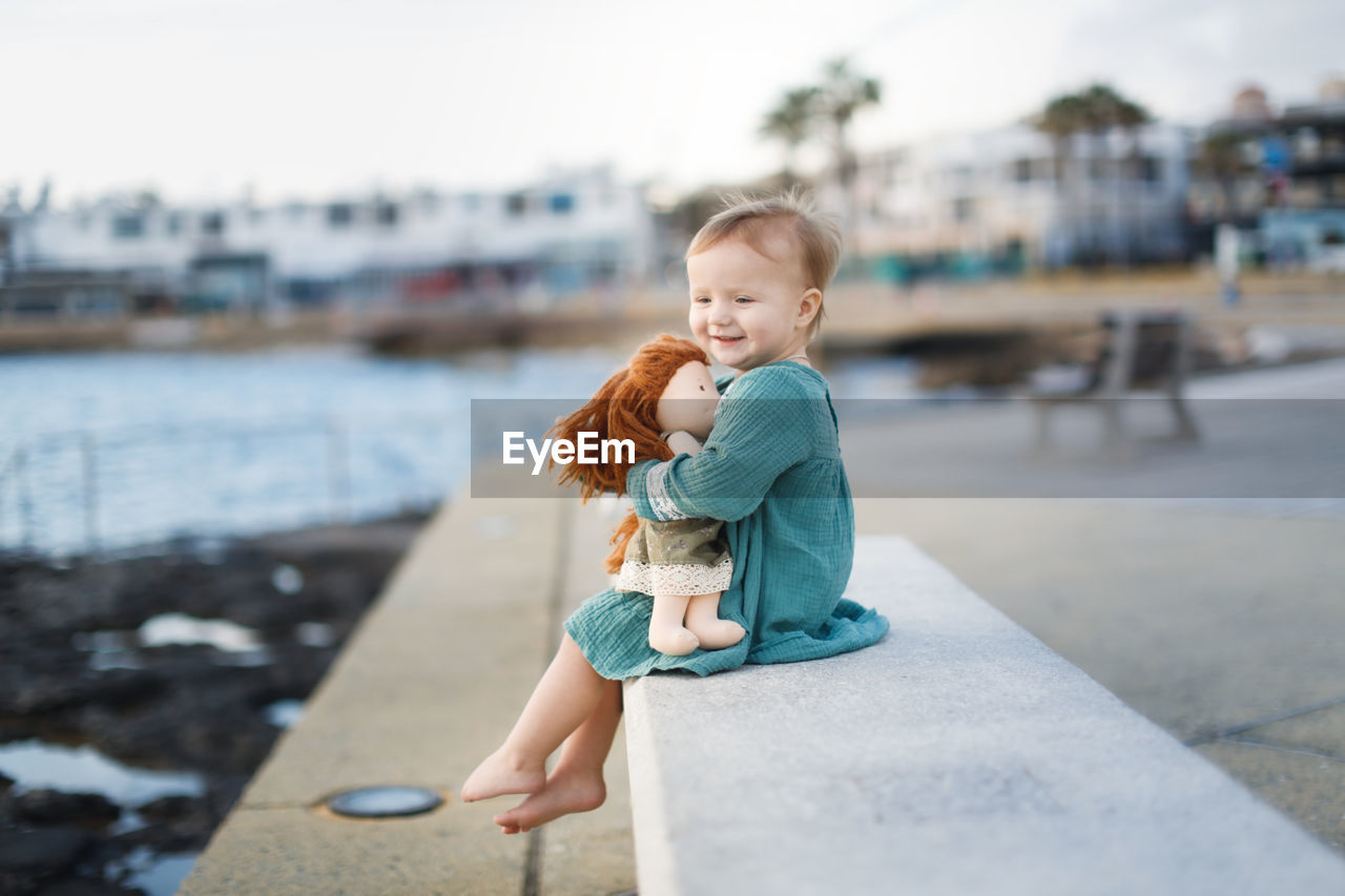 Side view of girl sitting on retaining wall