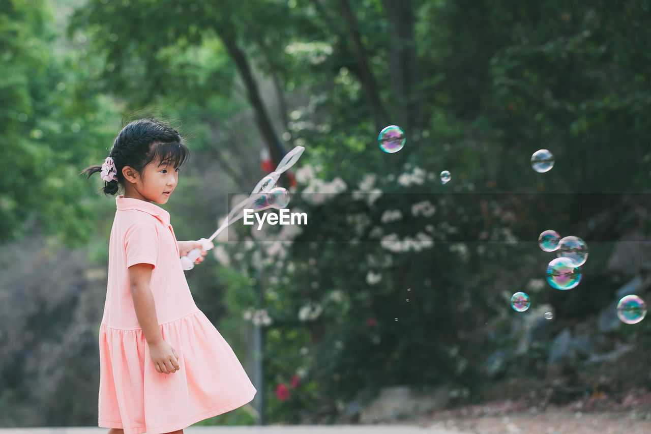 Cute girl blowing bubbles outdoors