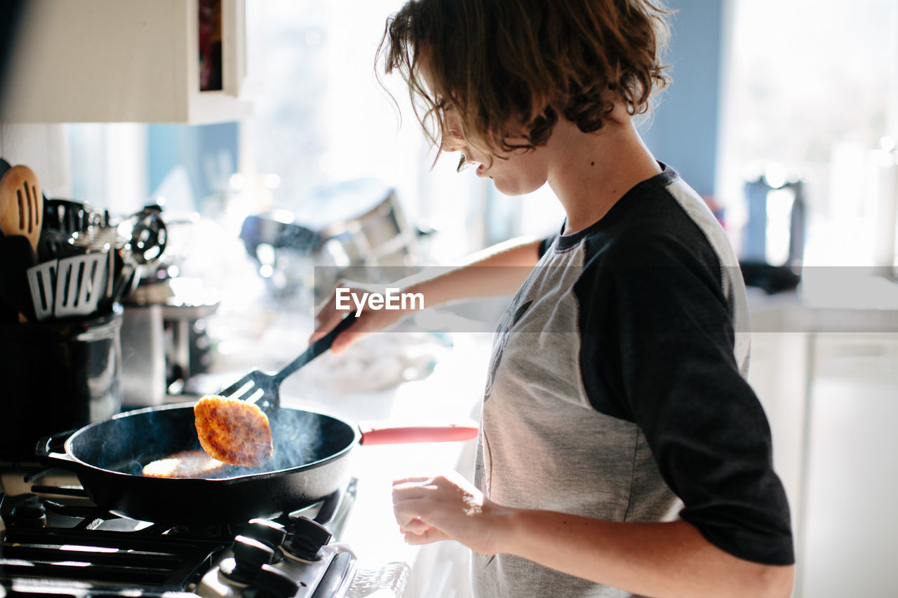 Teen girl flips a steaming hash brown in a cast iron pan