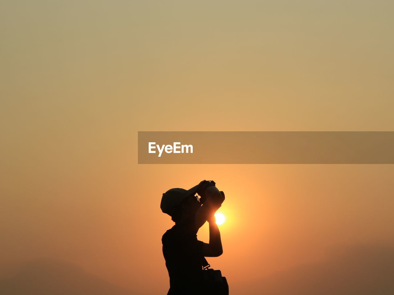 Silhouette man photographing against sky during sunset