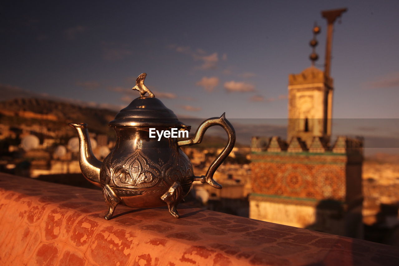 Metallic teapot on table against town