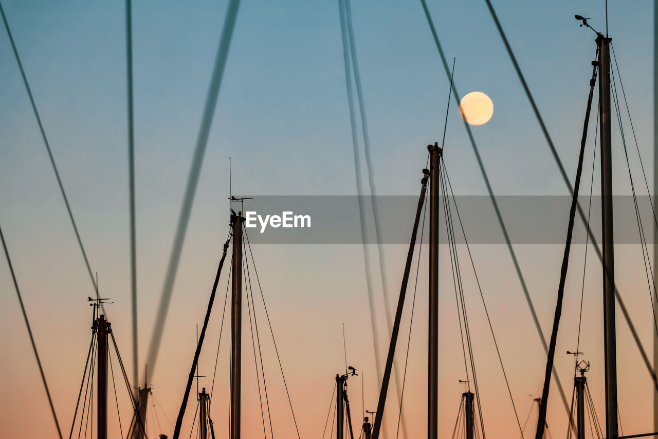 LOW ANGLE VIEW OF SAILBOATS AGAINST SKY AT SUNSET