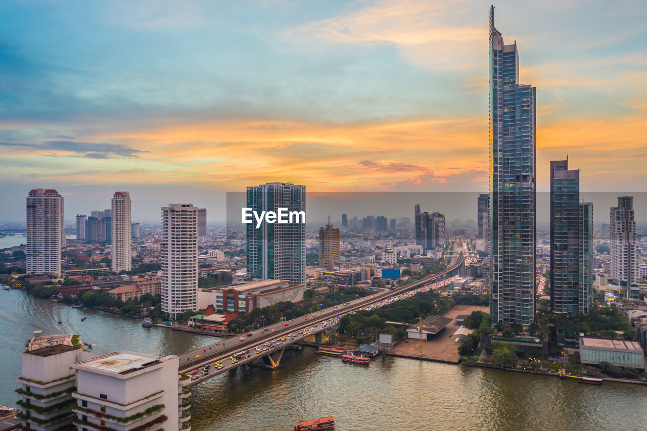 Panoramic view of river amidst buildings against sky during sunset