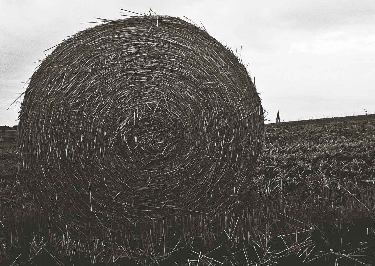 Close-up of hay bale on landscape below against the sky
