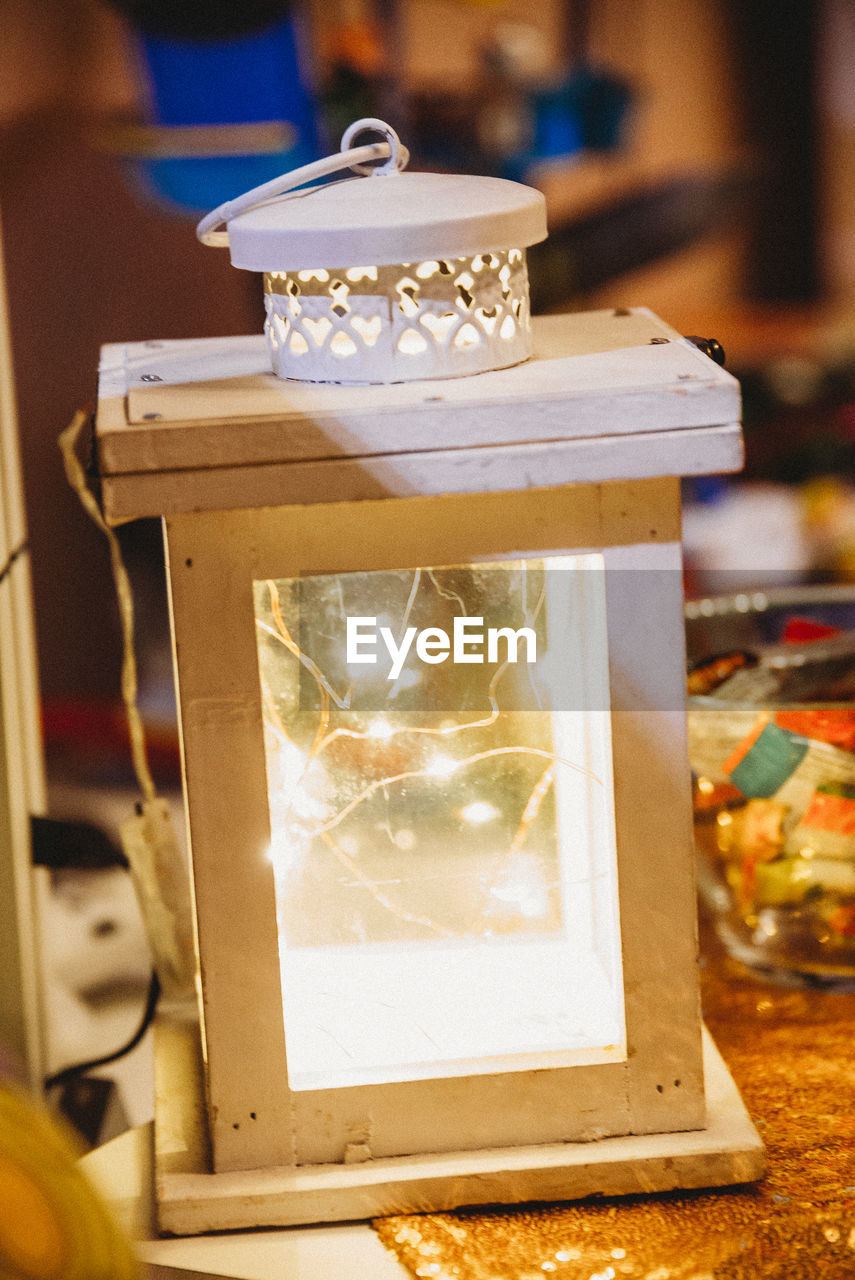 CLOSE-UP OF LIT CANDLE IN GLASS ON TABLE
