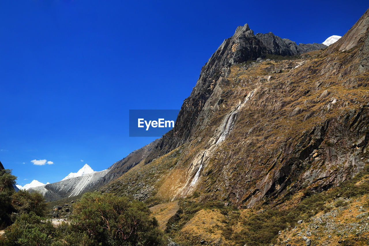 Low angle view of rocky mountain peak against blue sky