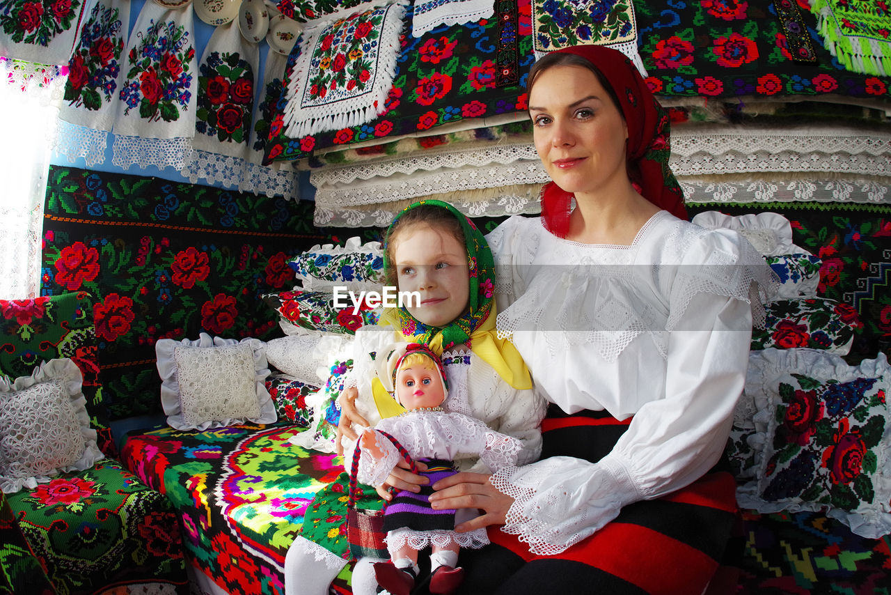 FULL LENGTH OF MOTHER AND GIRL SITTING ON WALL