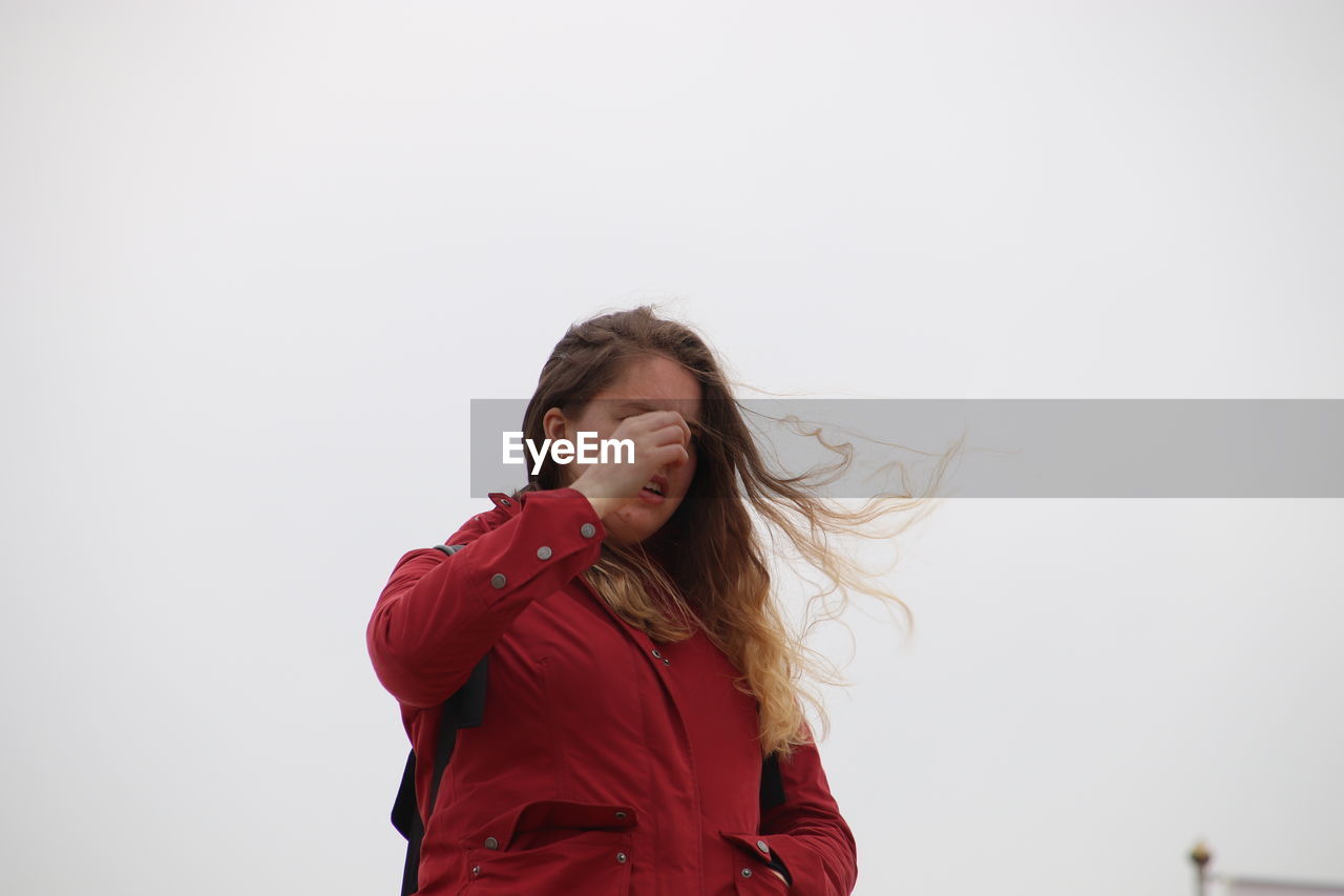 Low angle view of young woman standing against clear sky