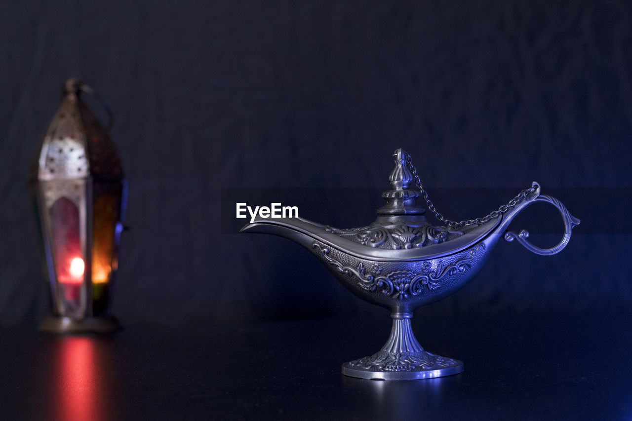 Close-up of magic lamp on table against black background