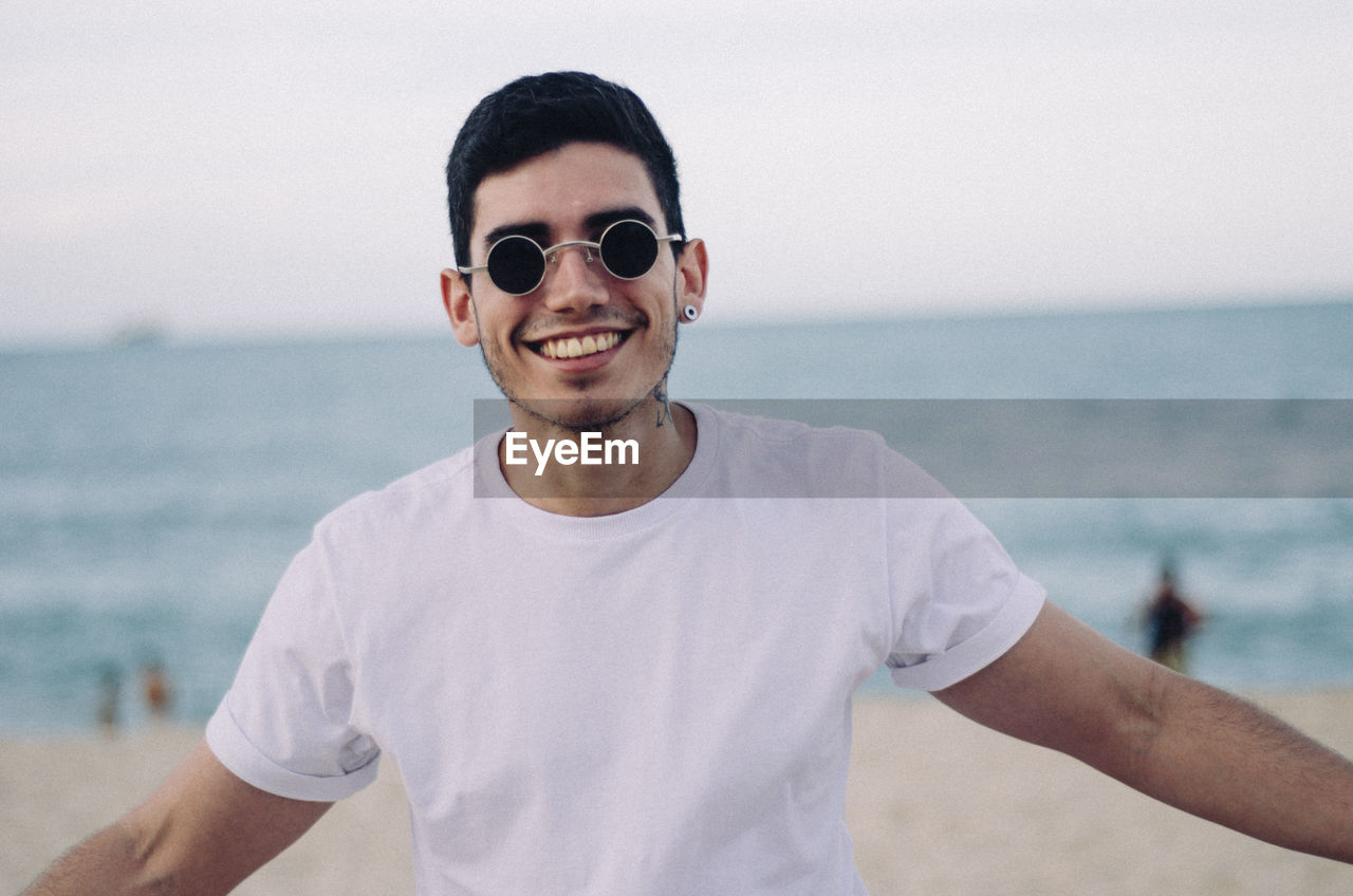 Portrait of smiling young man standing against sea