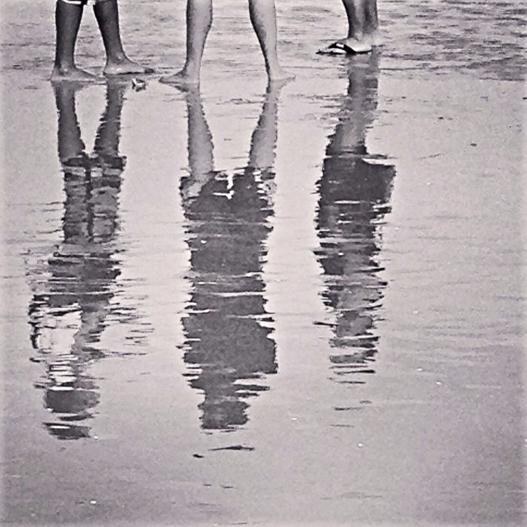 Reflection of three people on beach