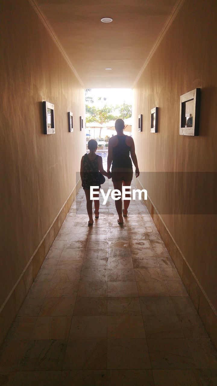 REAR VIEW OF COUPLE WALKING IN CORRIDOR OF BUILDING