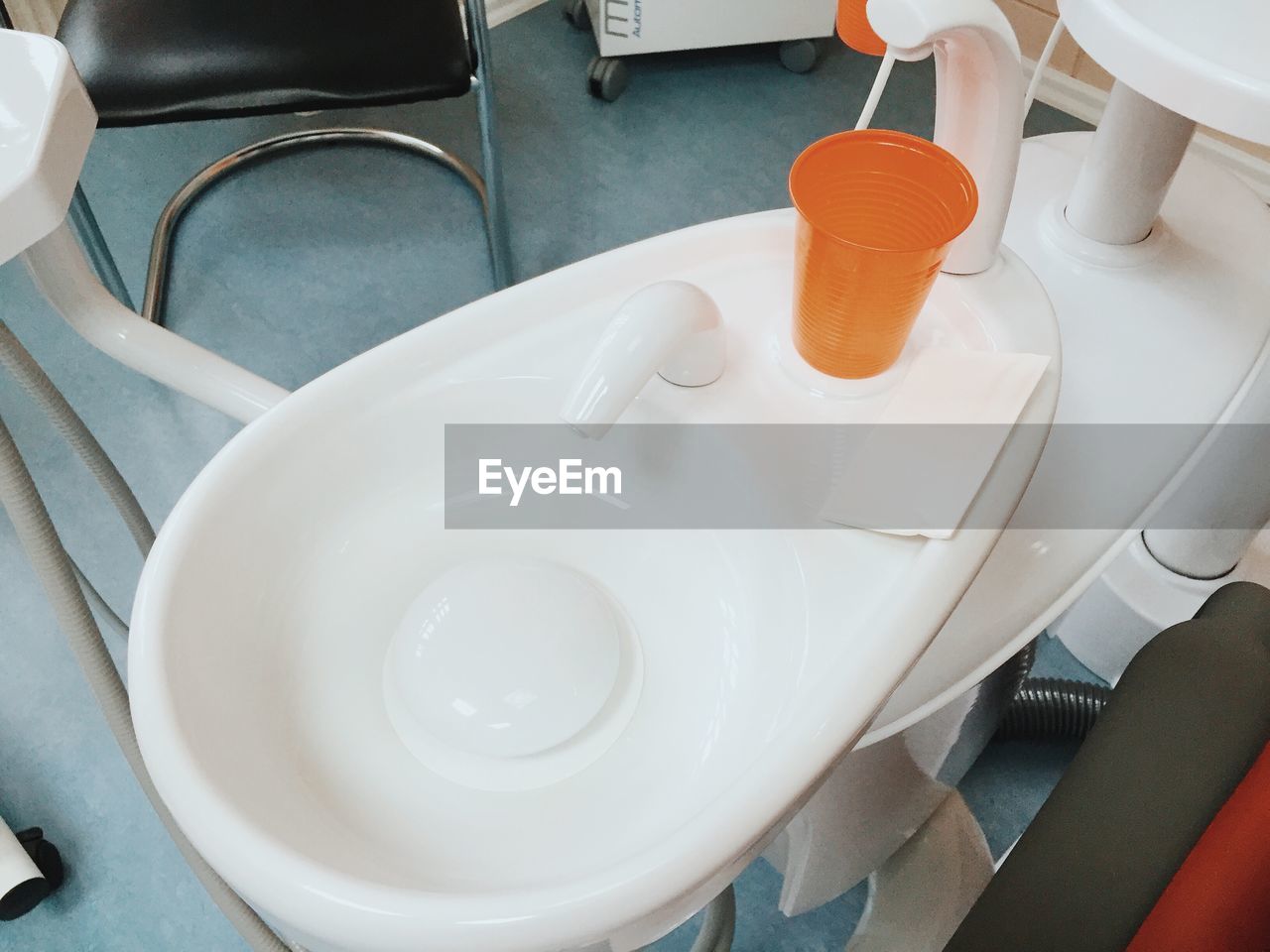 High angle view of orange disposable cup by sink at dentist clinic
