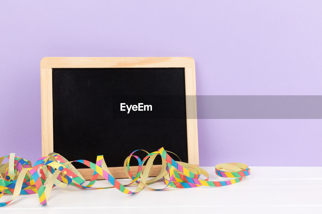 Close-up of blank slate and streamer against gray background