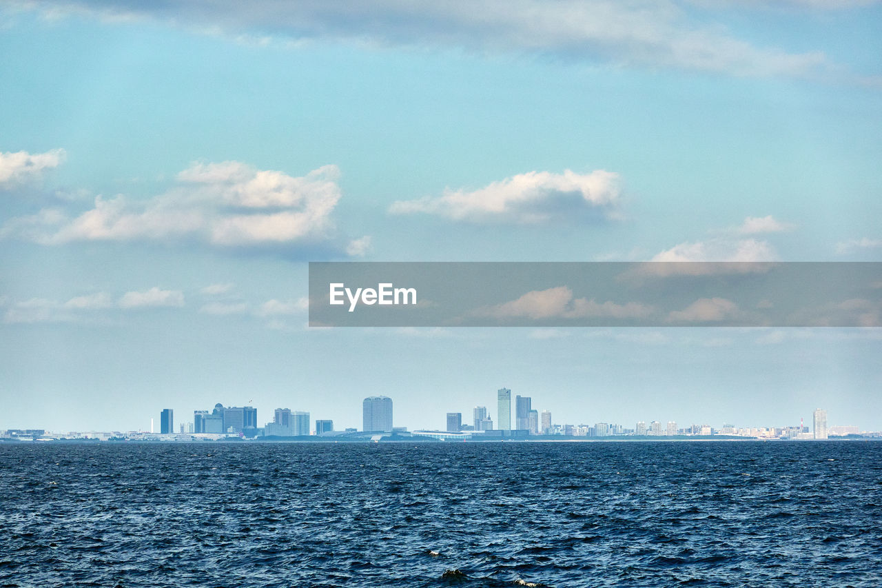 Sea by buildings against sky in city