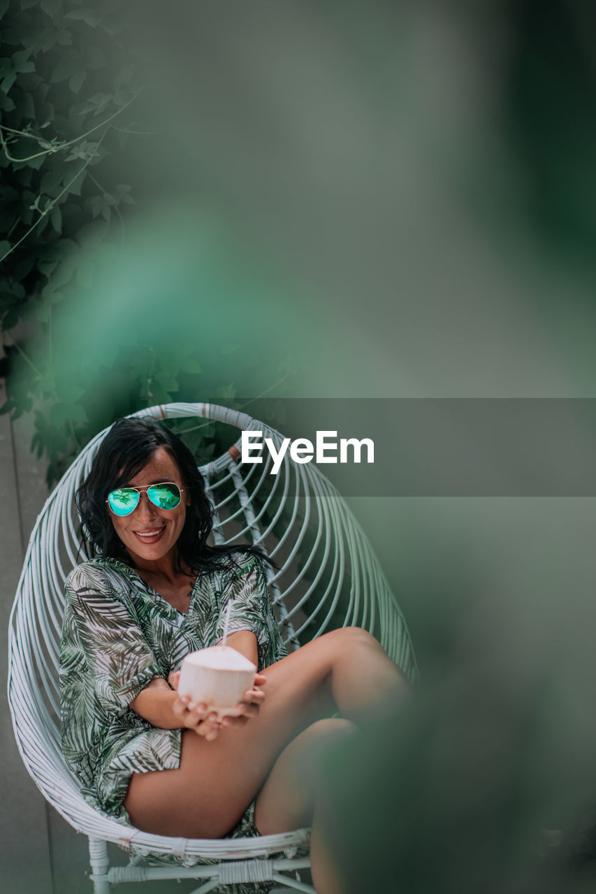 Portrait of woman wearing sunglasses sitting outdoors