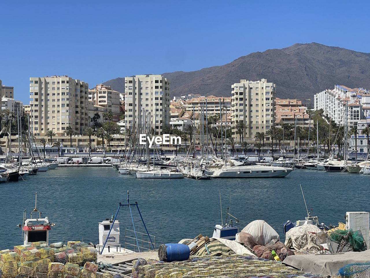 water, marina, architecture, nautical vessel, dock, transportation, harbor, mode of transportation, building exterior, built structure, sea, ship, city, nature, sky, building, moored, coast, no people, clear sky, vehicle, sailboat, port, travel destinations, day, mountain, travel, cityscape, bay, land, yacht, sunny, beach, blue, town, pier, outdoors, residential district, boat, watercraft, tourism, mast, landscape