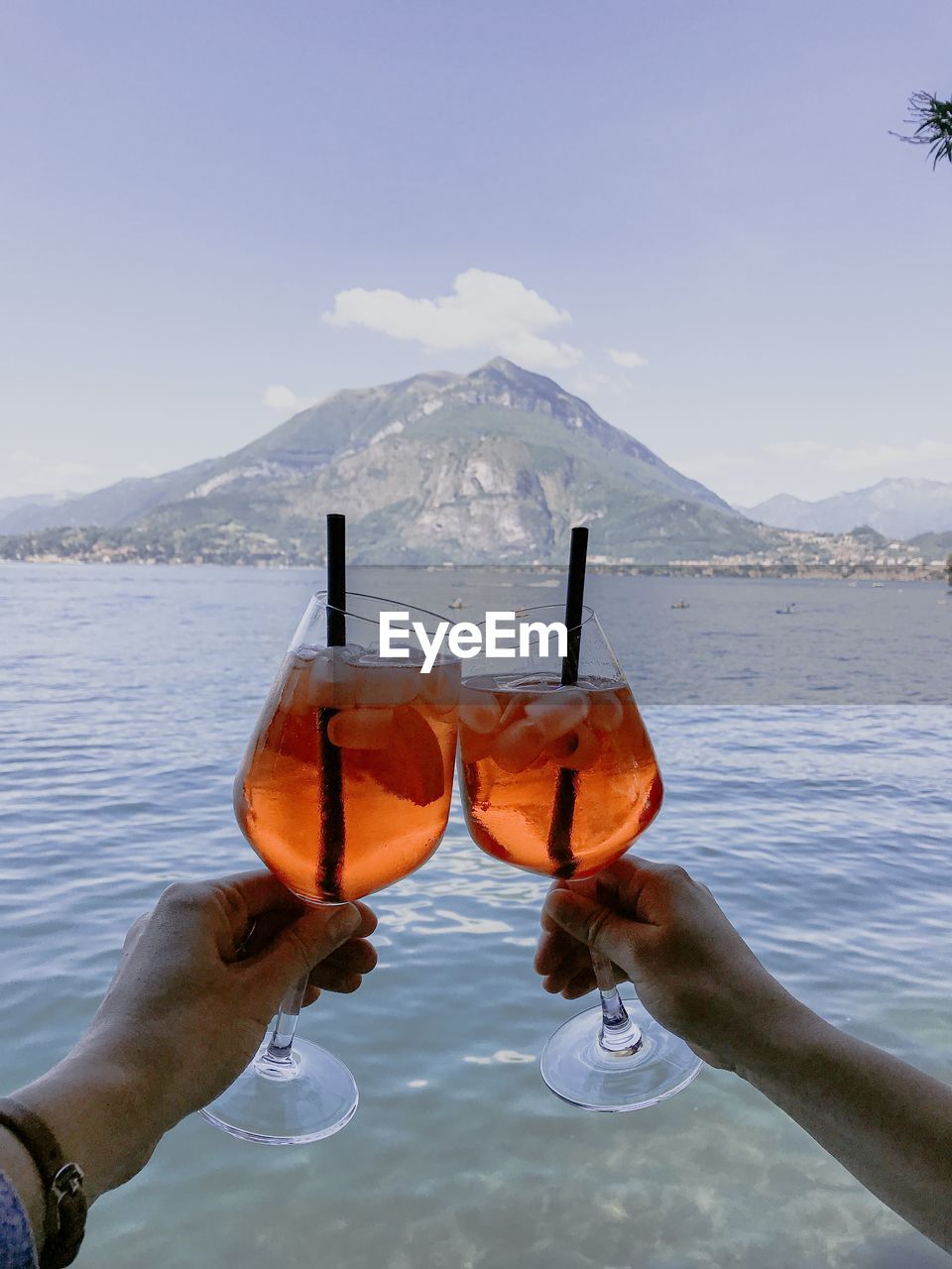 Close-up of hand holding drink against sky