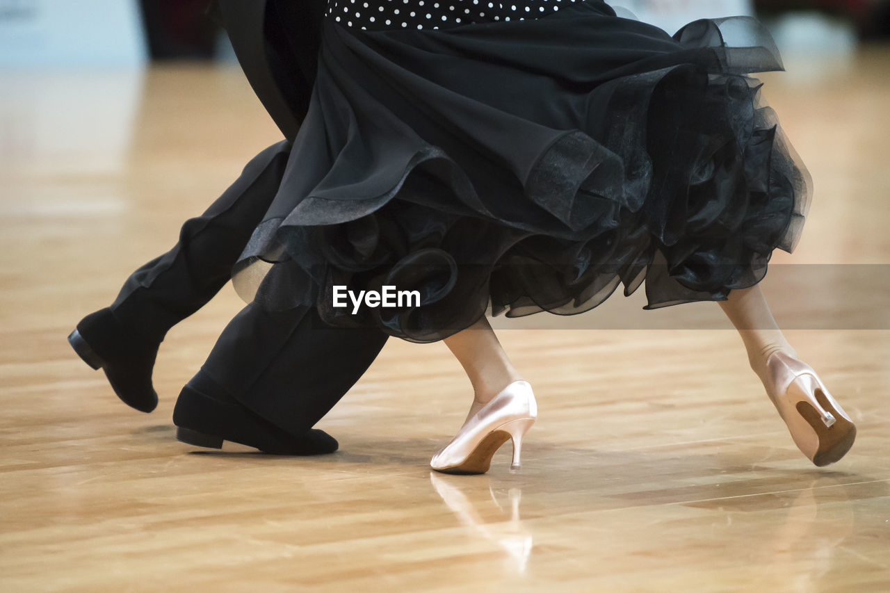 Low section of couple dancing on hardwood floor