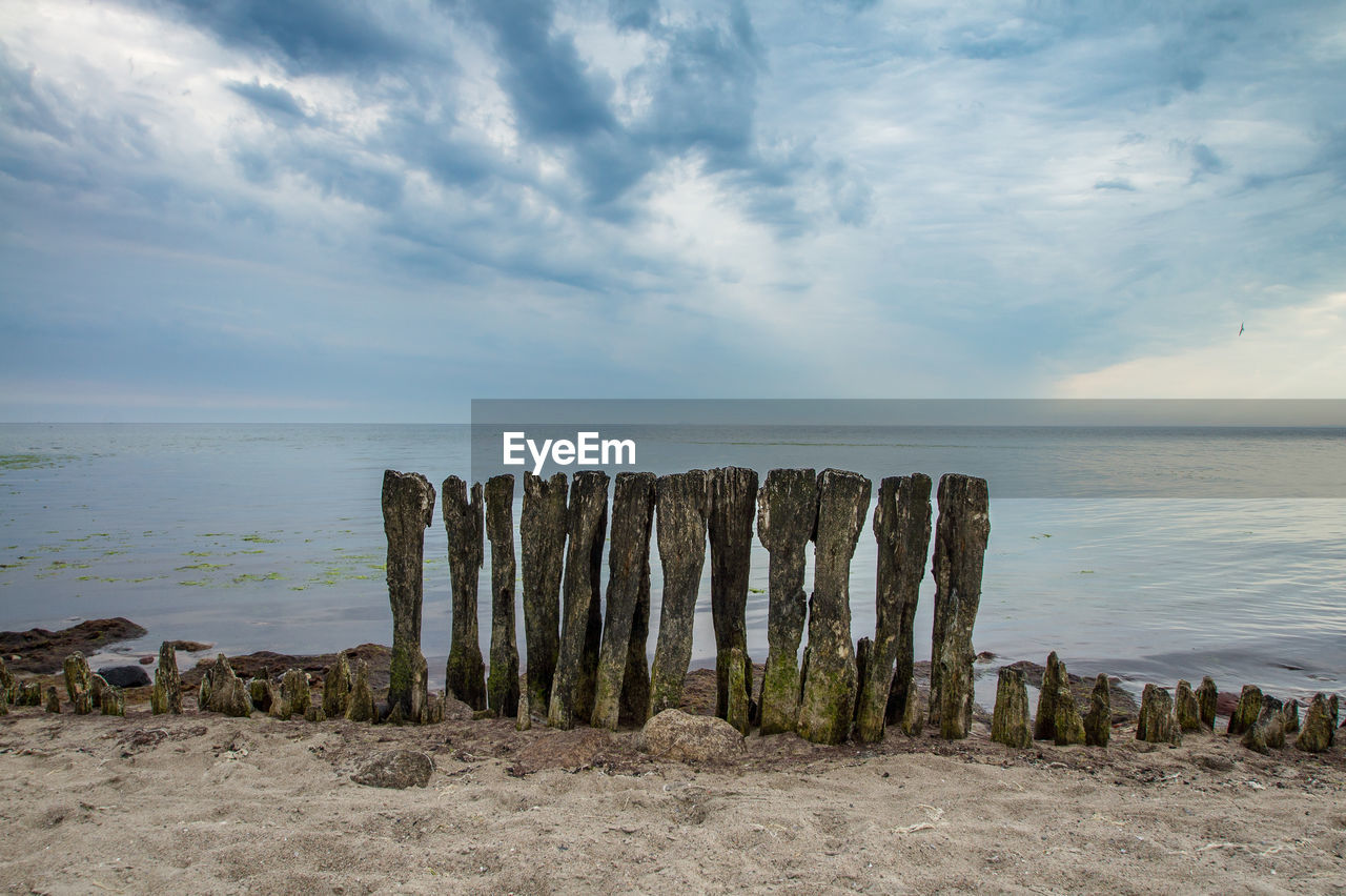 Wooden posts on beach against sky