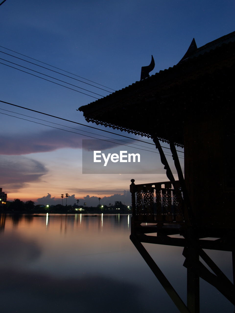 SILHOUETTE BUILDINGS BY LAKE AGAINST SKY AT SUNSET