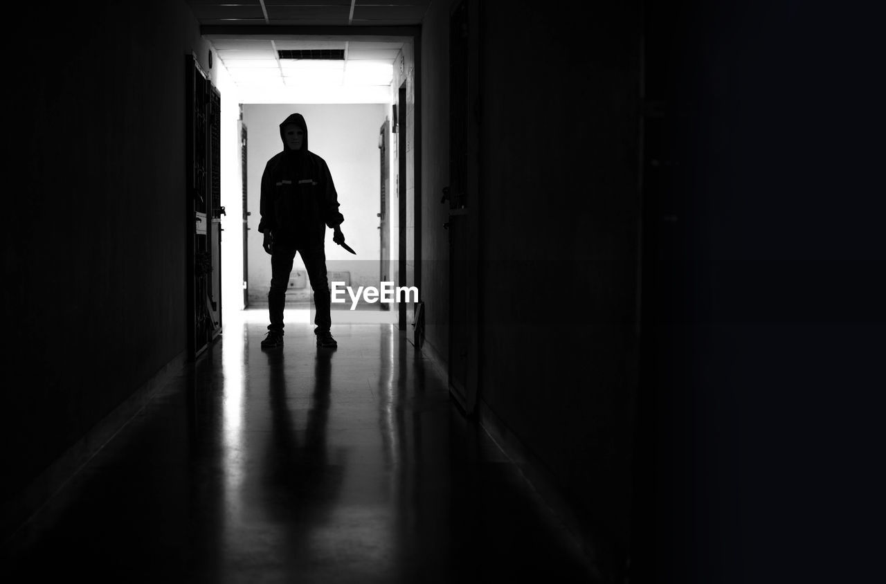 REAR VIEW OF MAN WALKING IN BUILDING