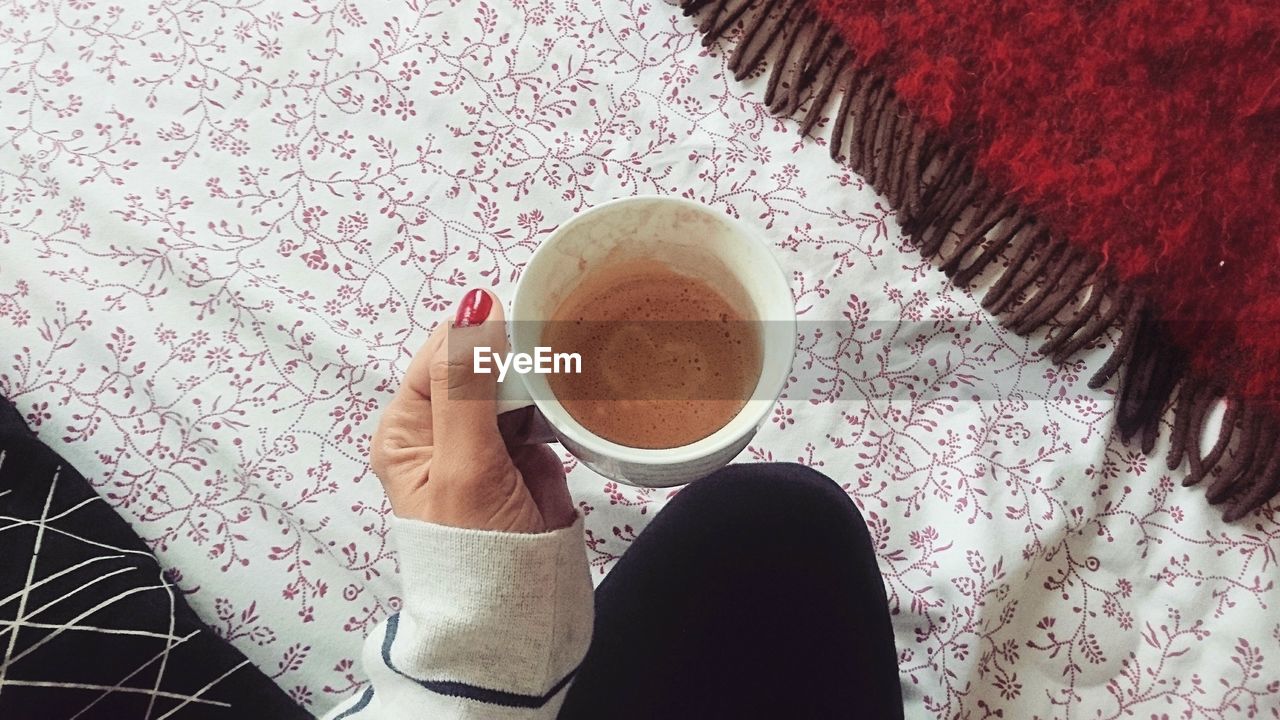 DIRECTLY ABOVE SHOT OF WOMAN HOLDING COFFEE CUP